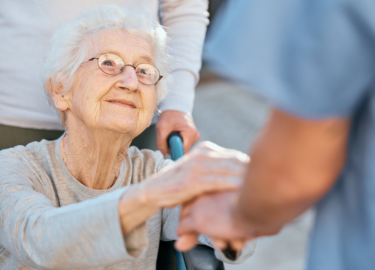 Elderly woman receiving mobility assistance from caregiver